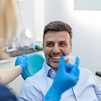 Patient smiling at orthodontic assistant holding clear aligner